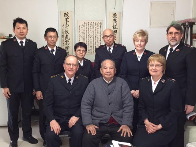 Le Général André Cox, la commissaire Silvia Cox et d'autres officiers en visite chez le lieutenant Li (au milieu devant).