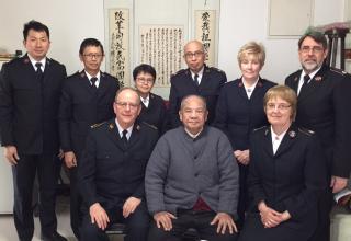 Le Général André Cox, la commissaire Silvia Cox et d'autres officiers en visite chez le lieutenant Li (au milieu devant).